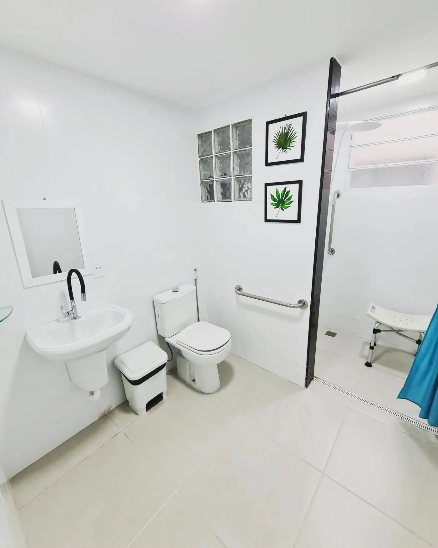 Banheiro adaptado da LARES, com barra de apoio, cadeira de banho e box sem degrau