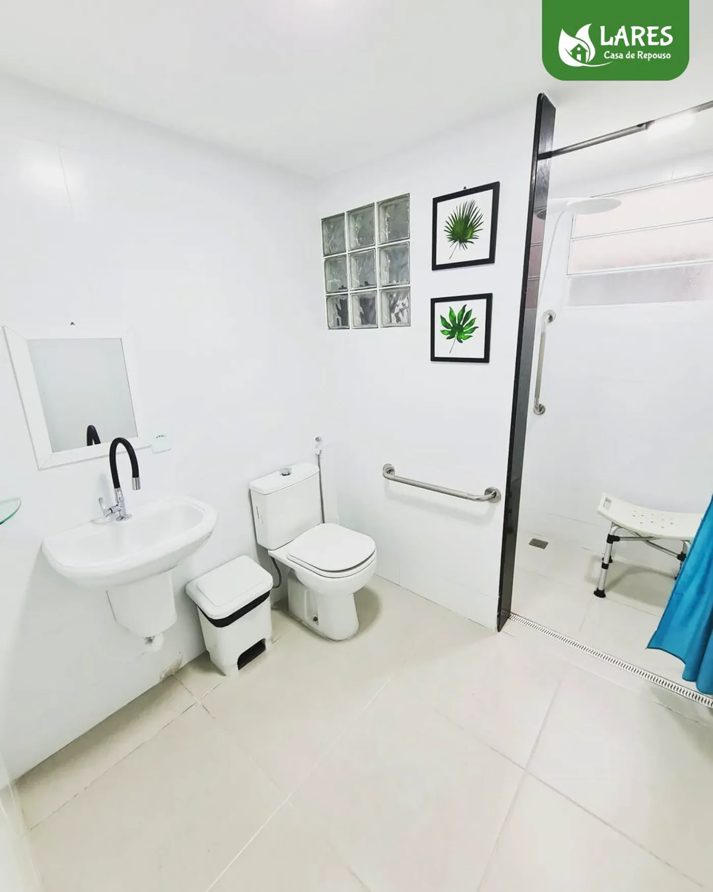 Banheiro adaptado da LARES, com barra de apoio ao lado do vaso e box sem degrau