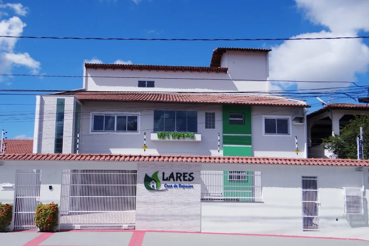 Fachada da LARES Casa de Repouso, no Jardim Asteca: casa de dois andares em branco e verde, com o letreiro da casa no muro