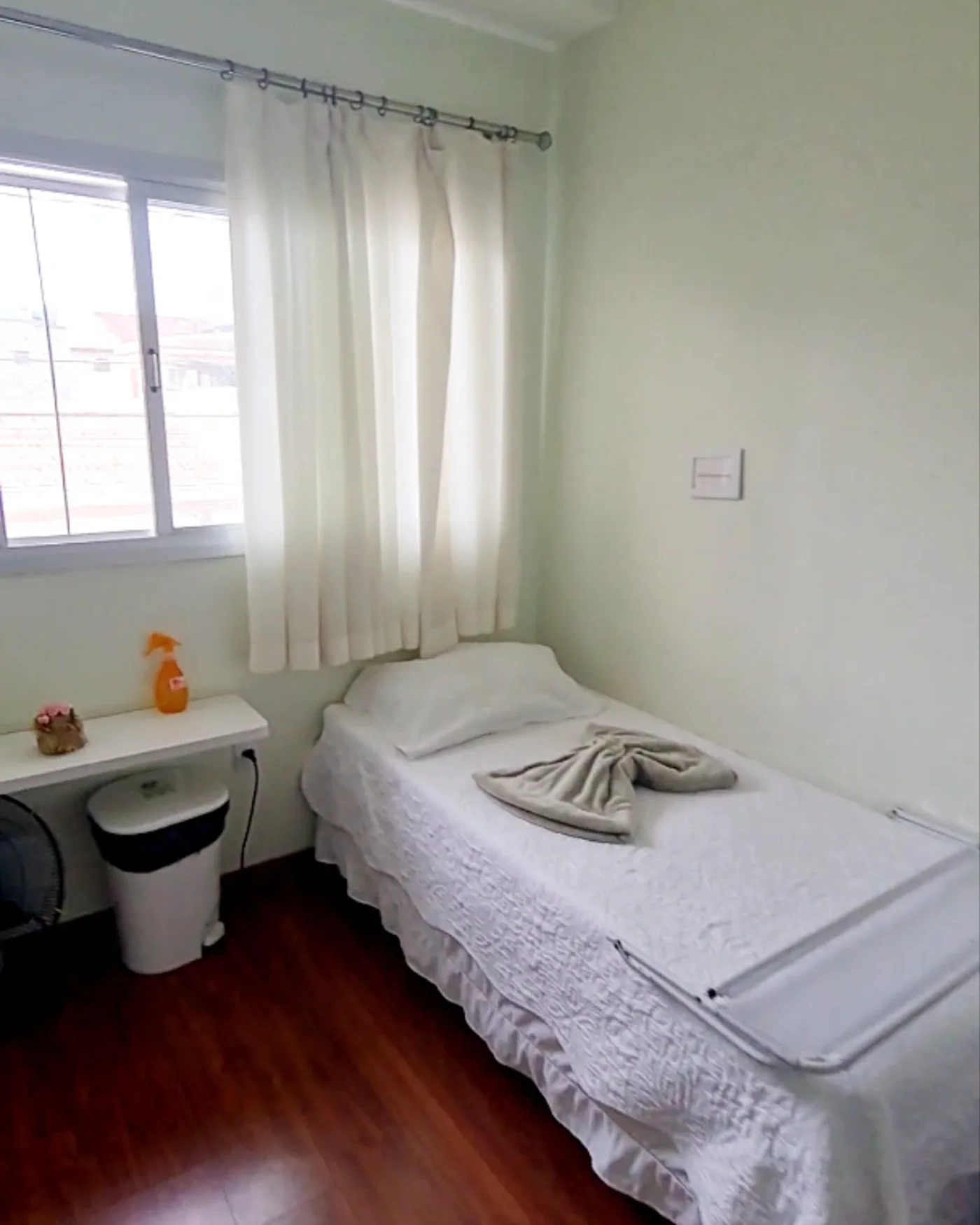 Quarto da LARES com cama individual, criado-mudo e janela ampla