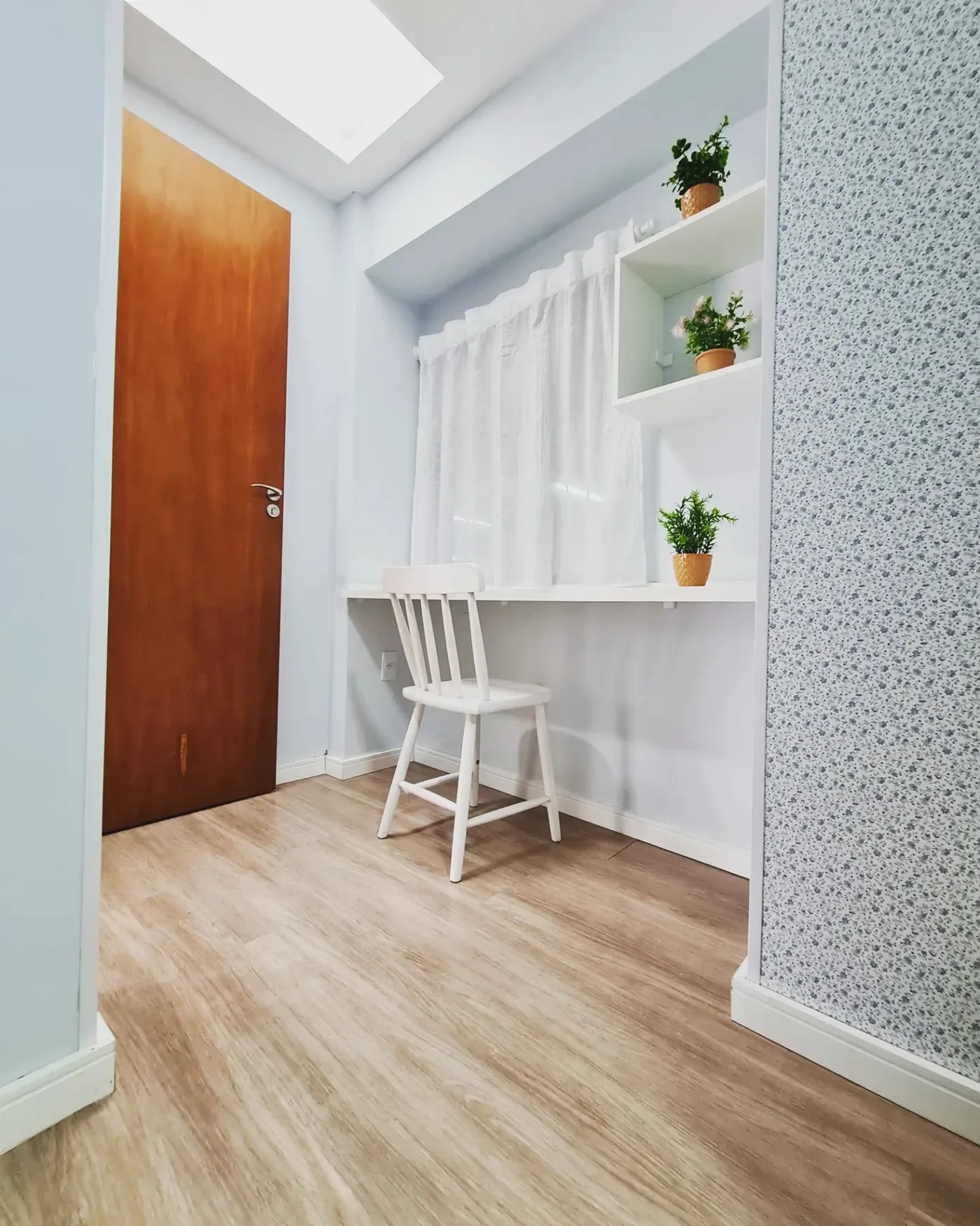 Canto de estudo de um quarto da LARES, com escrivaninha, cadeira branca e prateleiras com plantas
