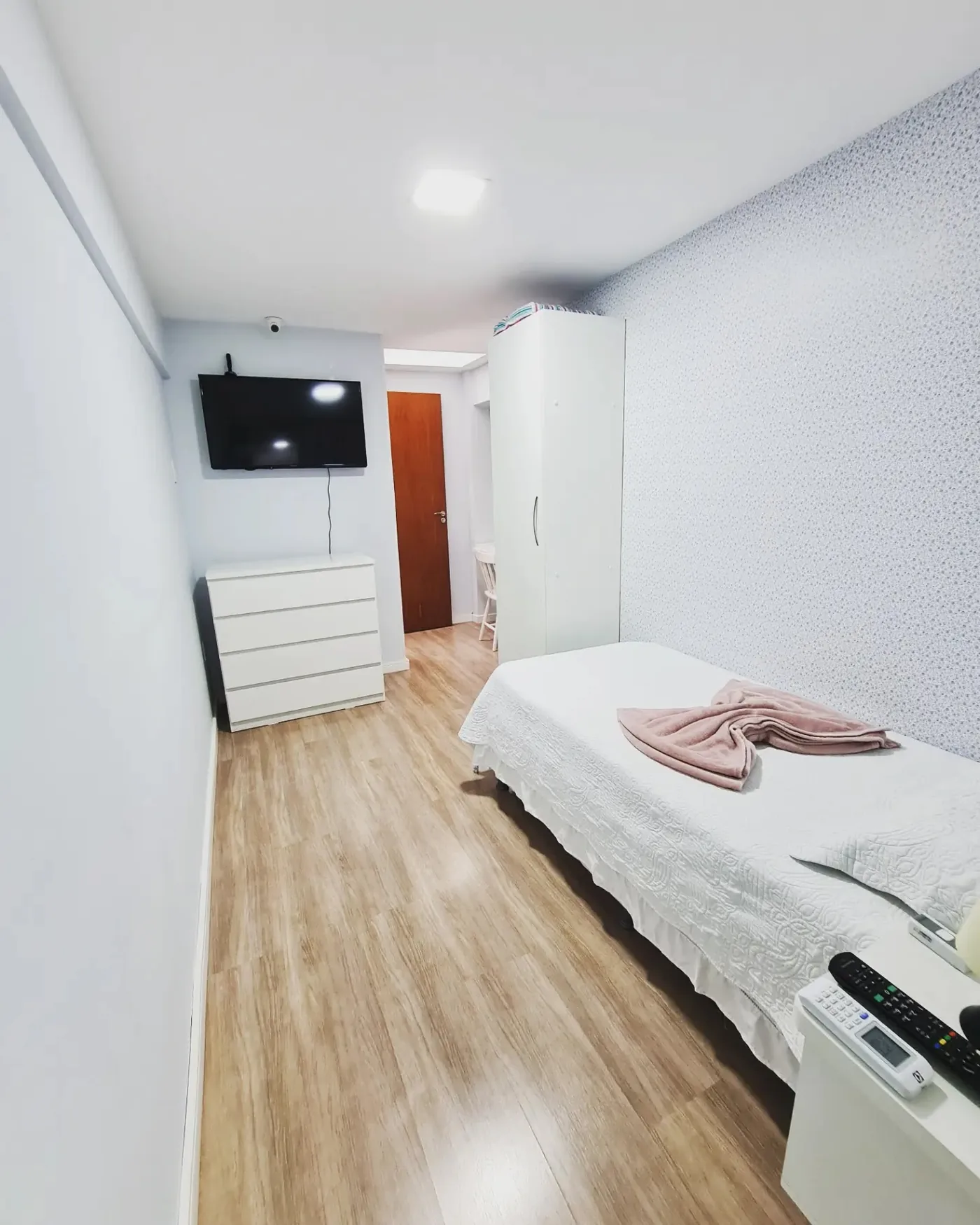 Suíte individual da LARES, com cama, armário, cômoda e televisão