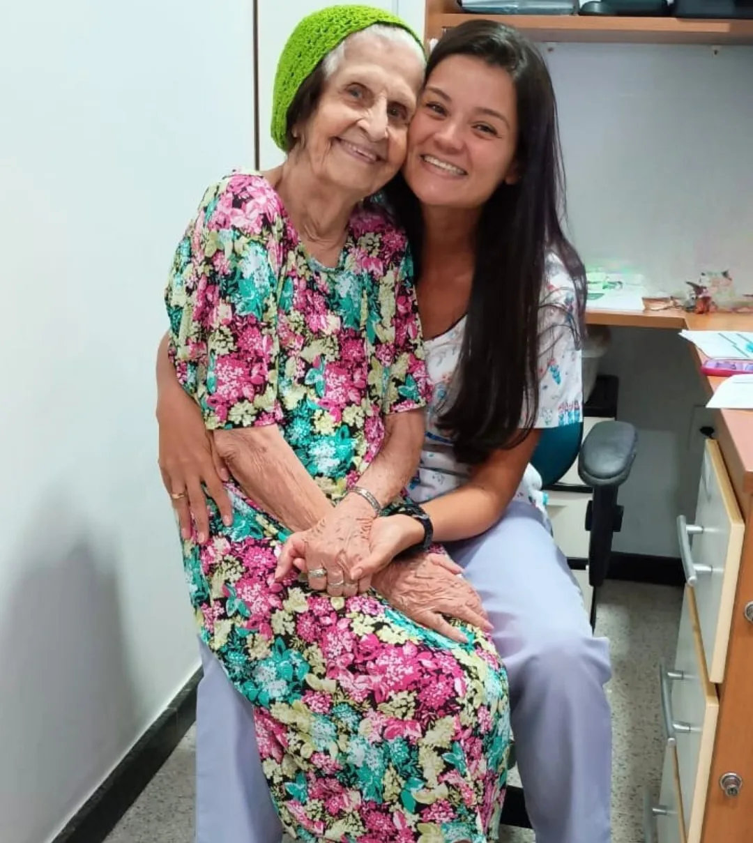 Auxiliar de enfermagem da LARES abraçada com uma moradora, as duas sorrindo