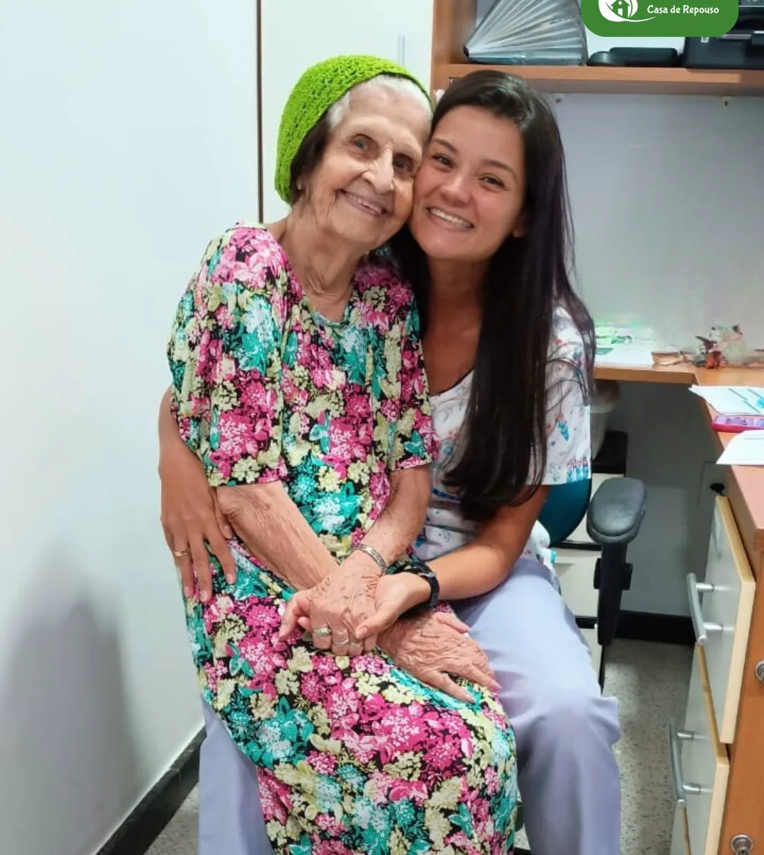 Cuidadora da LARES ao lado de uma moradora, as duas sorrindo