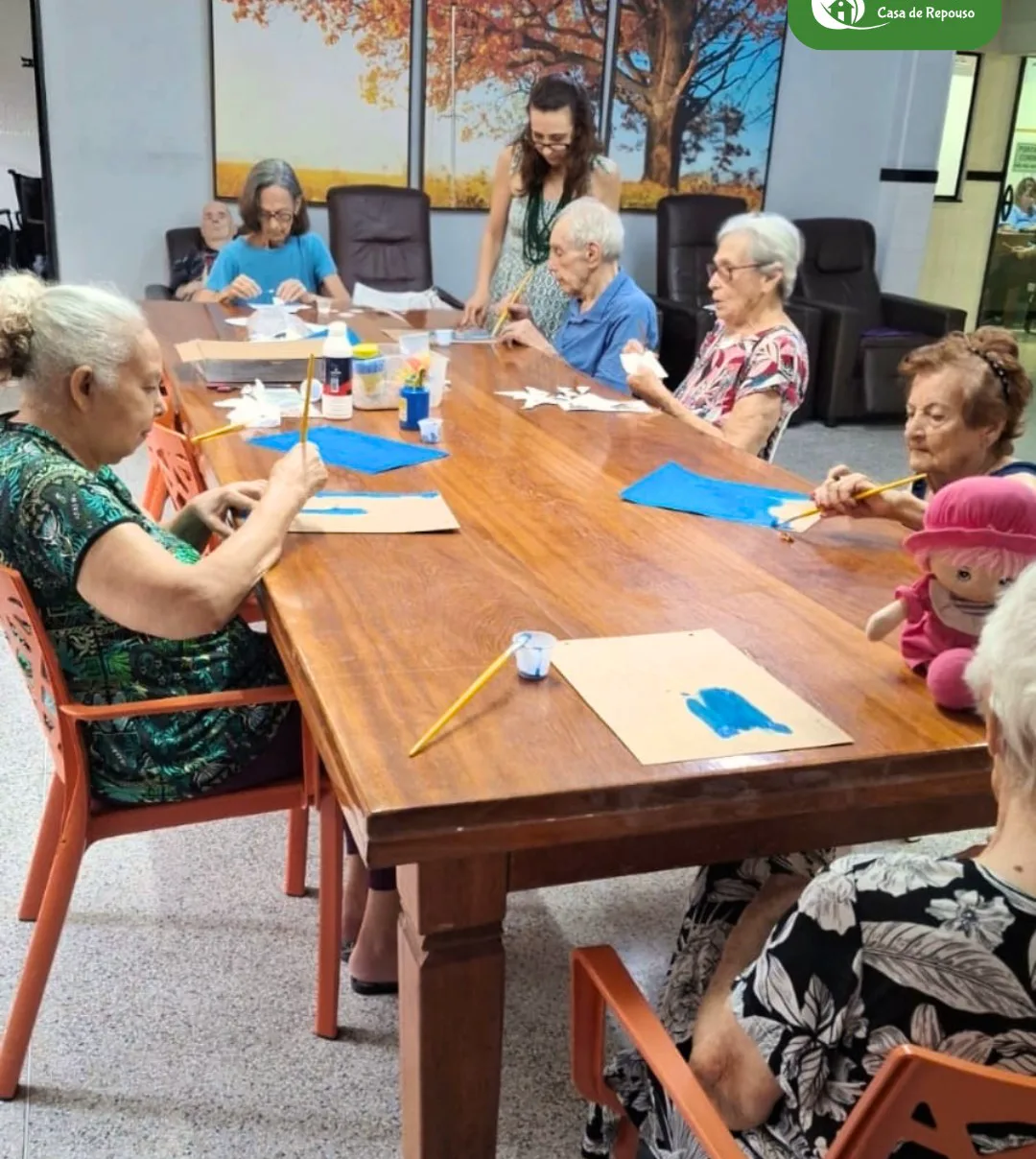 Moradores da LARES reunidos em volta da mesa grande numa oficina de pintura